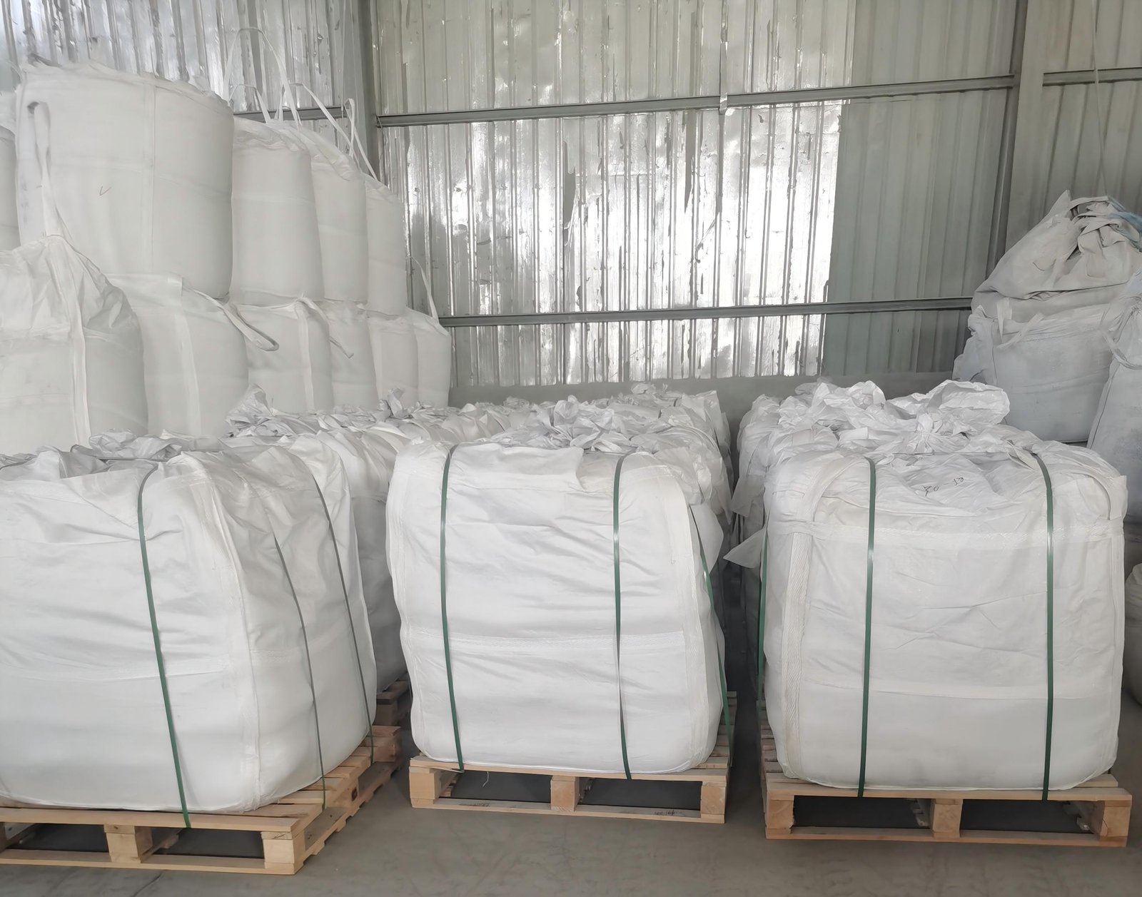 Fused silica finished-batch warehouse — 1-ton jumbo bags on wooden pallets with green strapping, ready for export