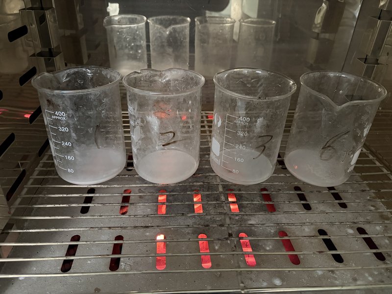 Moisture test in drying oven — glass beakers numbered 1 to 4 for loss-on-drying measurement of fused silica powder at the Chemsize lab