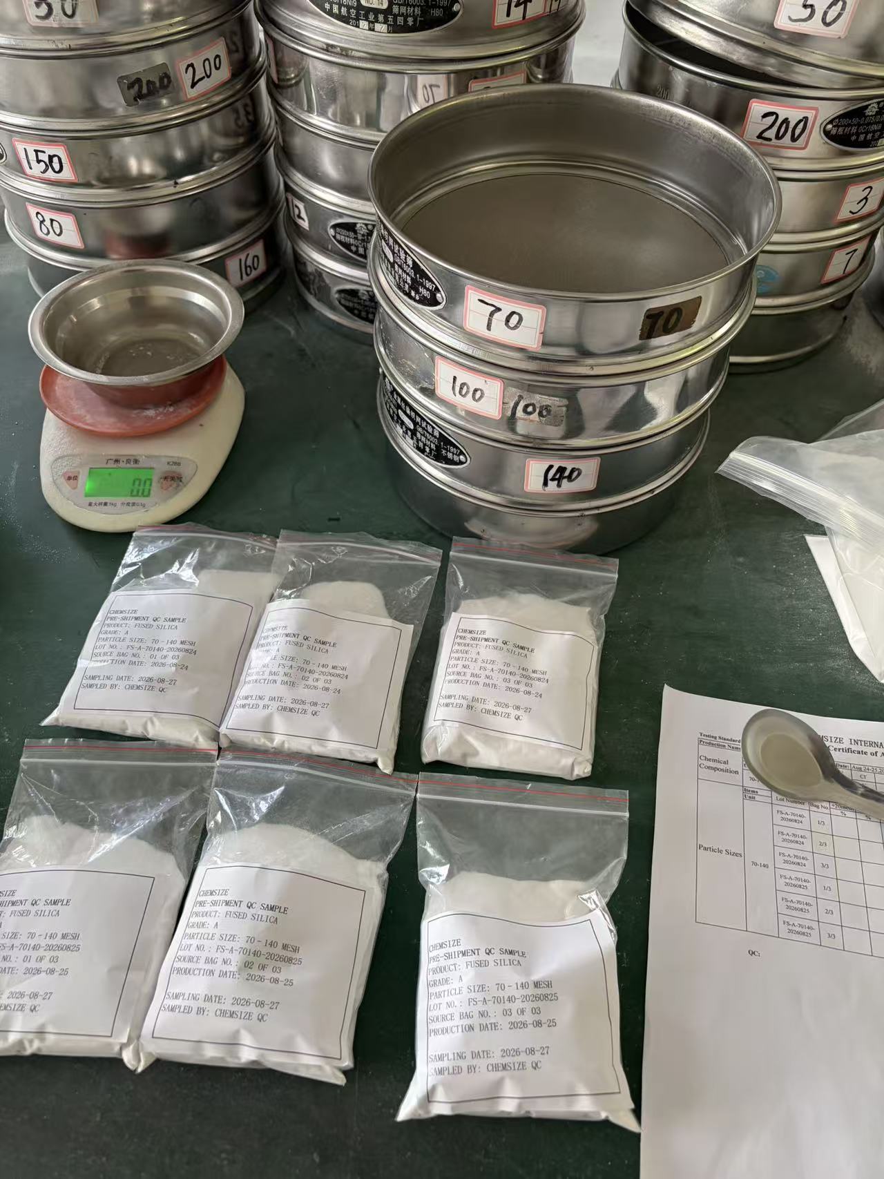 Six labelled source-bag samples of fused silica arranged beside a laboratory sieve stack with mesh screens 70, 100, 140 and 200, ready for individual particle-size testing.