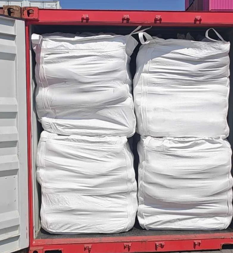 Two rows of white flexible intermediate bulk containers (FIBC jumbo bags) of fused silica stacked inside an open export container, with the left-hand door of the container swung open.